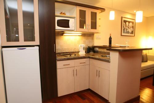 a small kitchen with white cabinets and a microwave at Hotel Ankara Suites in Salta