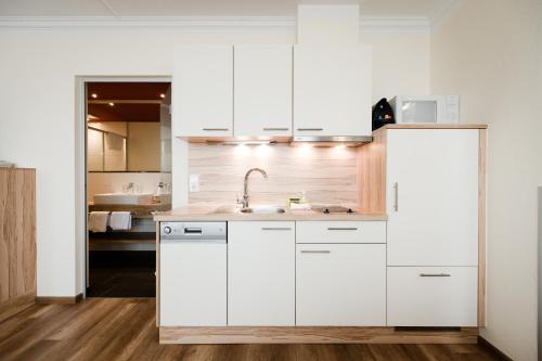 a kitchen with white cabinets and a sink at Aparthotel Dorfplatzl Garni in Tux