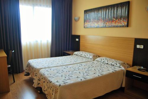 a hotel room with two beds and a window at Hotel Piedra in Perlora
