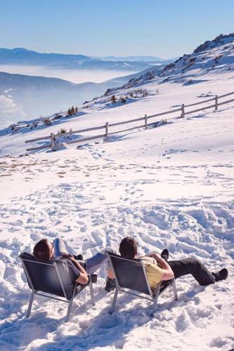 two people sitting in chairs in the snow at Planinska kuća "Sedam Vlašića" in Vlasic