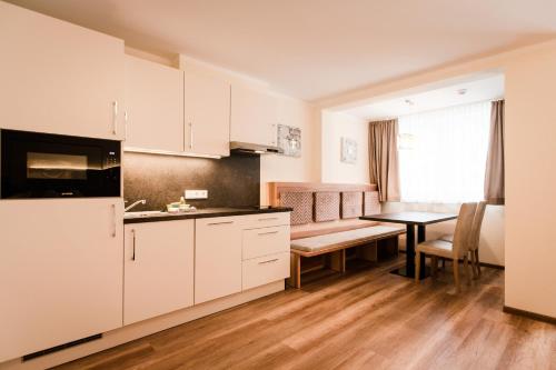 a kitchen with a table and a dining room at Aparthotel Dorfplatzl Garni in Tux