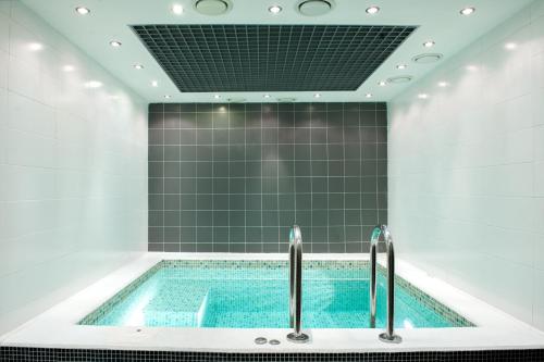 a swimming pool in a bathroom with green tiles at AMAKS Congress Hotel in Rostov on Don