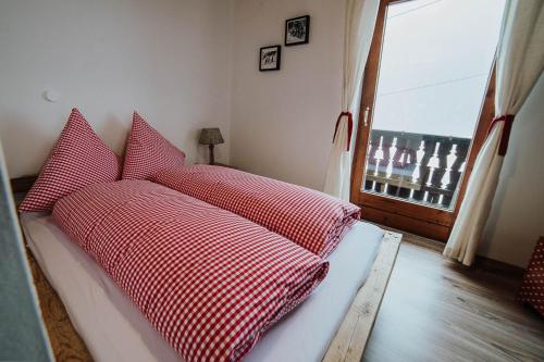 a bed with red and white pillows in a room with a window at Berggasthof Hochpröller in Sankt Englmar