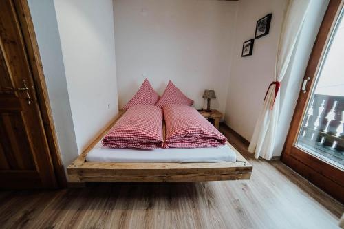 a bed with four red pillows on it in a room at Berggasthof Hochpröller in Sankt Englmar