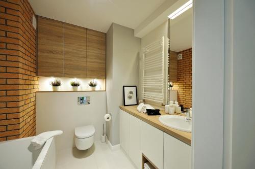 a bathroom with a sink and a toilet and a mirror at JTB Nautica Aparthotel in Szczecin