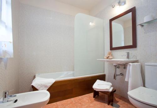 a bathroom with a tub and a sink and a toilet at Hotel Rural El Fundil in El Pino