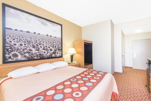 a hotel room with a bed with a large picture on the wall at Super 8 by Wyndham Wichita South in Wichita