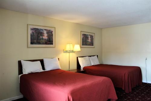two beds in a hotel room with red sheets at Cascades Motel - Chattanooga in Chattanooga