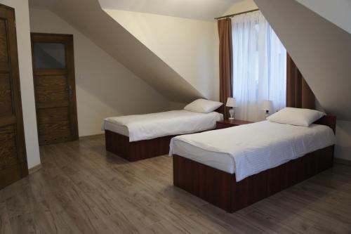 Una habitación de hotel con dos camas y una ventana. en Pensjonat Perła Pienin, en Grywałd
