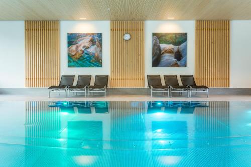 a pool with chairs in a room with paintings at Pradas Resort Brigels in Breil/Brigels