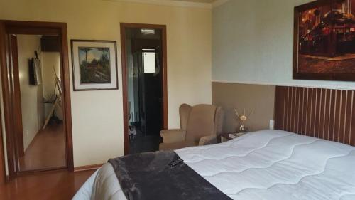 1 dormitorio con 1 cama blanca grande y 1 silla en Apartamento Gramado, en Gramado