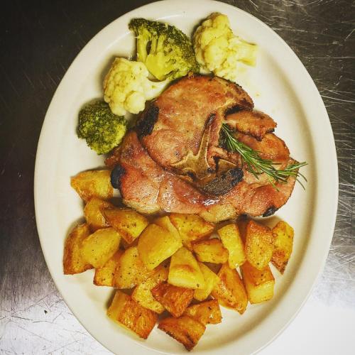 a plate with a chicken and potatoes and broccoli at Naturalmente Boutique Bungalows y Cocina Mediterránea in Las Lajas