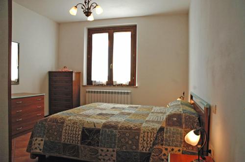 a bedroom with a bed and a dresser and two windows at Casale il Colle Deruta in Deruta