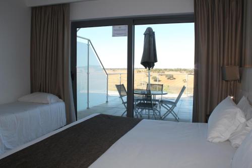 a bedroom with a bed and a balcony with a table at Hotel O Gato & Spa in Odivelas