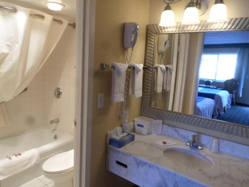 a bathroom with a sink and a toilet and a mirror at Travelodge by Wyndham Ogallala in Ogallala