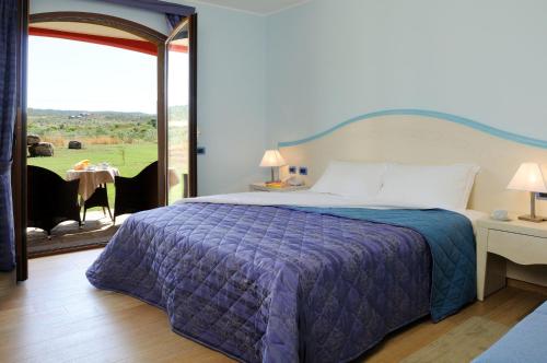 a bedroom with a bed and a patio with a table at Hotel Sa Cheya Relais & Spa in Alghero