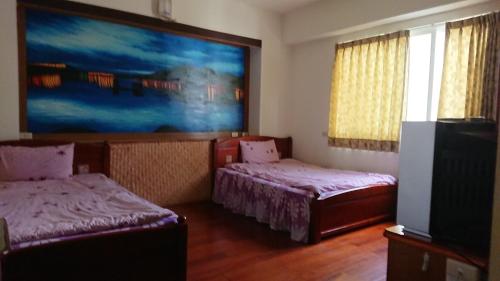 Habitación con 2 camas y una pintura en la pared. en Da Lin Gu Wan Homestay en Yuchi
