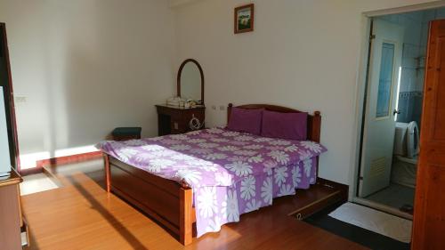 um quarto com uma cama com um edredão roxo em Da Lin Gu Wan Homestay em Yuchi