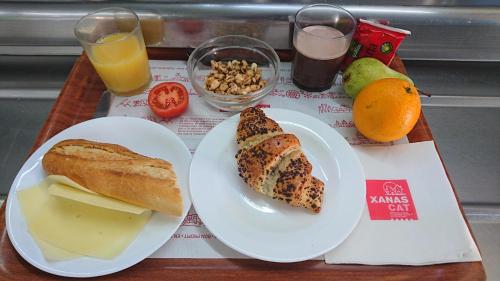 een dienblad met een bord brood, kaas en fruit bij Alberg Coma-ruga Xanascat in Comarruga