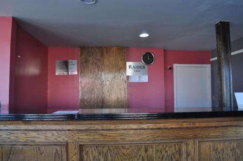 una barra con espejo y pared roja en Raider Inn en Lubbock