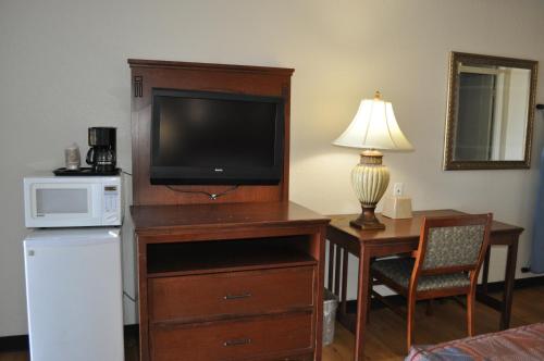 a room with a television and a desk with a microwave at Raider Inn in Lubbock