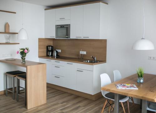 cocina con armarios blancos y mesa de madera en Haus NordQuartier, en Norderney