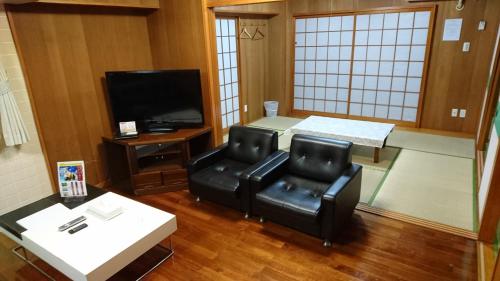 a waiting room with two chairs and a television at Kokusai Towns Inn in Naha