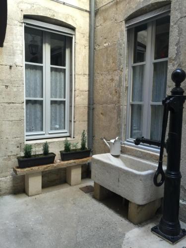 a stone sink in front of a building with windows at Le doux rendez-vous in Beaune