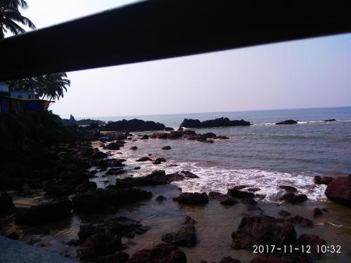 a view of a beach with rocks and the ocean at Om Ganesh Guest House Cliffside in Arambol
