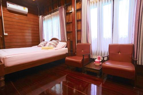 a small bedroom with a bed and two chairs at Bansuwan Homestay in Amphawa