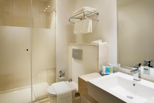 a bathroom with a toilet and a sink and a shower at St. George Hotel in Jerusalem