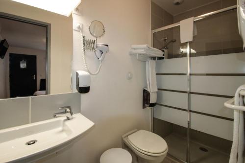 La salle de bains est pourvue d'un lavabo, de toilettes et d'un miroir. dans l'établissement Hôtel Le 15 Périgueux, à Coulounieix-Chamiers
