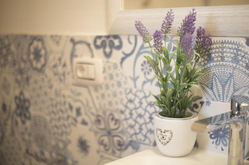 a white vase with purple flowers on a counter at La Valle del Tevere in Torrita Tiberina
