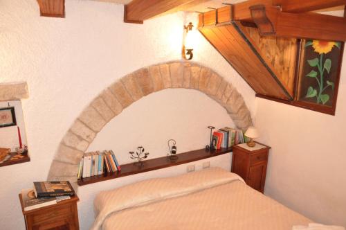 Un dormitorio con una cama con un arco de piedra encima. en Da Marzietta, en Asís