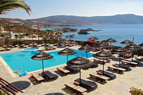 um resort com uma piscina com cadeiras e guarda-sóis em Aegean Village Beachfront Resort em Amoopi