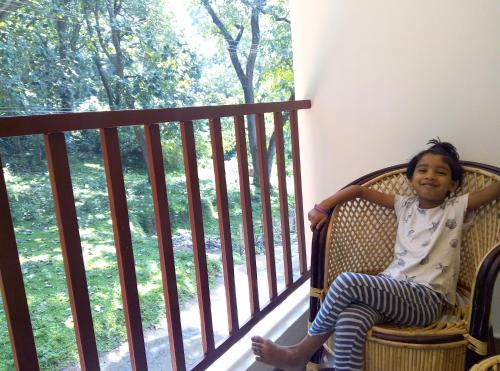 a little girl sitting in a chair on a balcony at Wild Window - Forest View Homestay in Thekkady