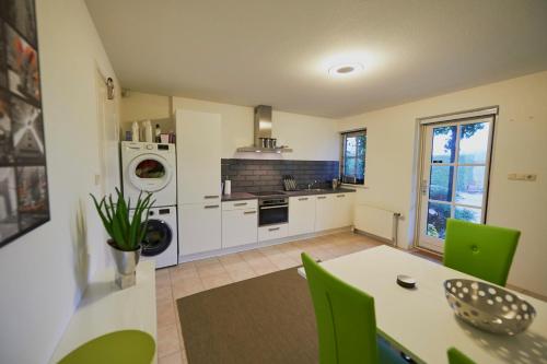 een keuken met een tafel en groene stoelen bij Harlingen Garden Apartment in Midlum