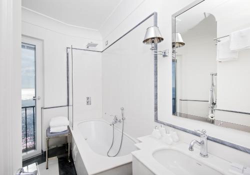 a white bathroom with a shower and a sink at Hotel Villa Franca in Positano
