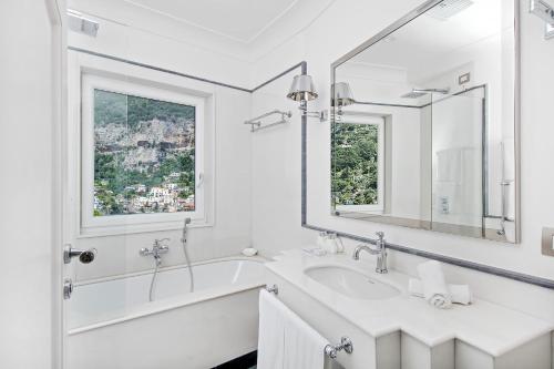 a white bathroom with a sink and a mirror at Hotel Villa Franca in Positano