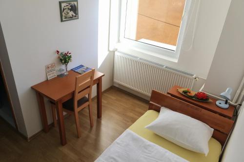a small bedroom with a desk and a bed and a table at Pansion Centar in Tuzla