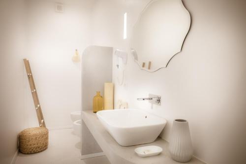 een witte badkamer met een wastafel en een spiegel bij Le Jardin Potager in Rome
