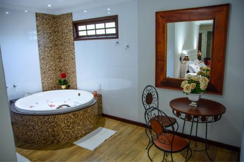 a bathroom with a tub and a table and a mirror at Pousada Valle das Colinas in Tiradentes