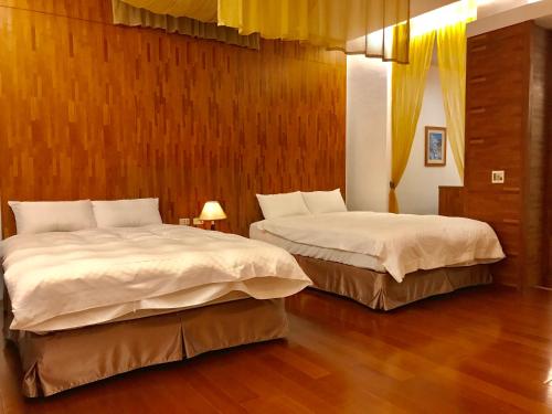 two beds in a room with wooden walls and wood floors at Hiye Fashion Motel in Dounan