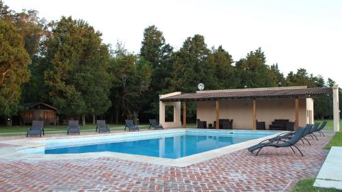 a swimming pool with chairs and a gazebo at Estancia Laguna Vitel in Chascomús