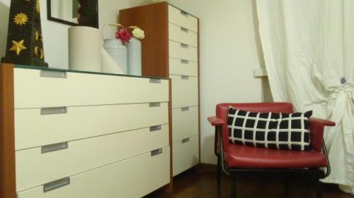 a bedroom with a dresser and a red chair at Charme&Chic in Trieste