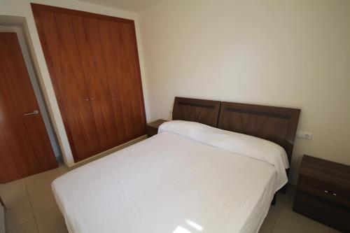 ロザスにあるmilleni 3222の白いベッドと木製キャビネット付きのベッドルーム1室