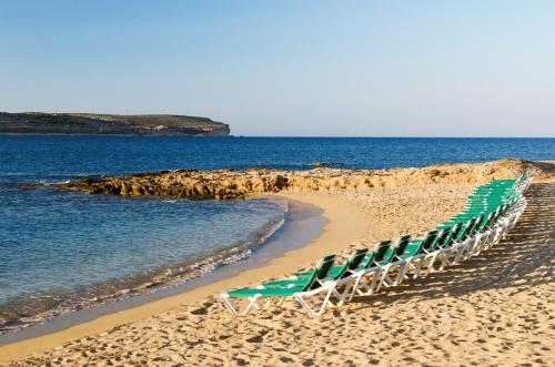 a row of lawn chairs on a beach at Paradise Bay Resort in Mellieħa