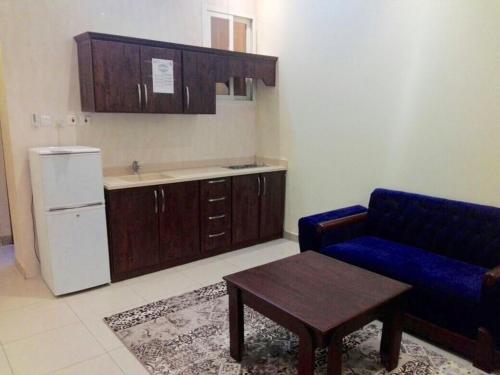 a kitchen with a couch and a table and a refrigerator at Najmat Sabbabah Furnished Units in Hail