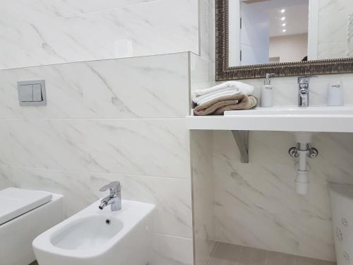 een witte badkamer met een wastafel en een spiegel bij Royal Center-3 rooms 3 tv in Chişinău