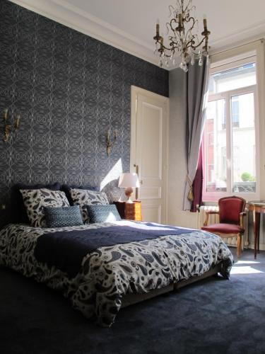 a bedroom with a large bed and a chandelier at La Bourgogne en Ville in Lille
